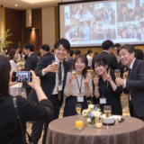 社内懇親会で写真を撮影する参加者と会場スクリーンのイメージ